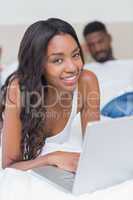 Relaxed woman using laptop on bed