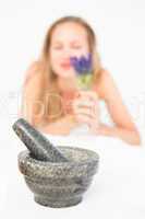 Beautiful blonde lying on massage table with mortar and pestle