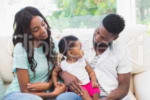 Happy couple with their baby girl on couch