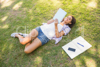 Pretty brunette relaxing in the grass and reading book