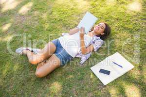 Pretty brunette relaxing in the grass and reading book