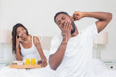 Relaxed couple having breakfast in bed together