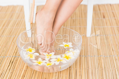 woman washing her feet in a bowl of flower