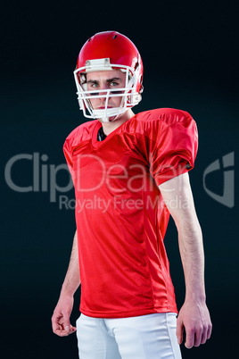A serious american football player taking his helmet looking at A serious american football player taking his helmet looking at