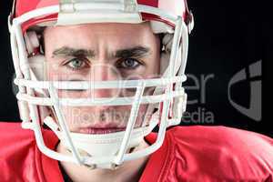 Portrait of a serious american football player taking his helmet
