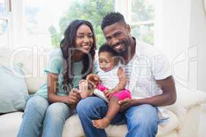 Happy couple with their baby girl on couch