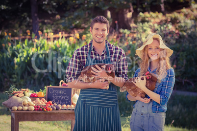 Happy farmers standing at their stall and holding chicken