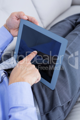 Relaxing businessman on a sofa with a tablet