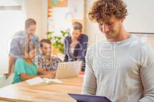 Casual businessman using digital tablet with colleagues behind i