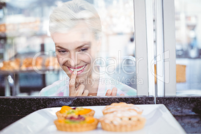 Hesitating pretty woman looking at fruit pie