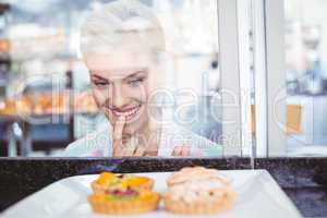 Hesitating pretty woman looking at fruit pie