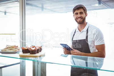 Handsome worker posing on the counter with a tablet