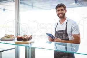 Handsome worker posing on the counter with a tablet