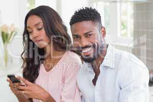 Happy couple using their phones at breakfast