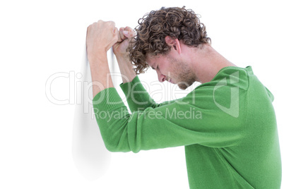 Sad casual man leaning against wall