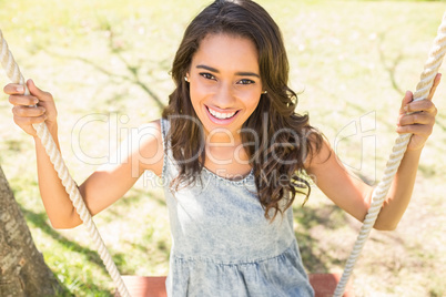 Pretty brunette swinging in park