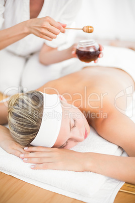 Therapist waxing womans back at spa center