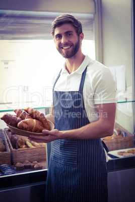 happy worker holding a basket of croissant