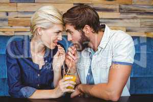 Cute couple on a date sharing a glass of orange juice