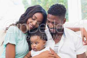 Happy couple with their baby girl on couch