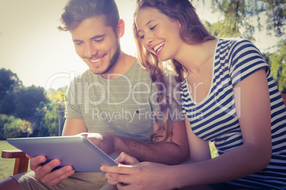Cute couple sitting on the bench and using tablet