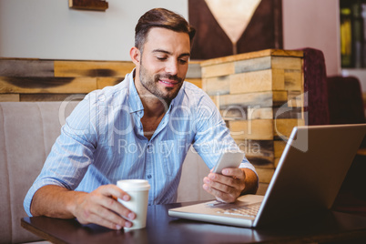 Smiling businessman sending a text message