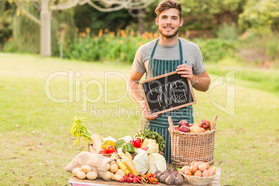 Handsome farmer standing at his stall and holding chalkboard