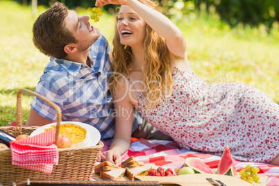 Young couple eating grapes at a picnic