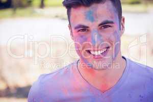Handsome man covered with powder paint in the park