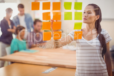 Concentrated businesswoman pointing post its on the wall