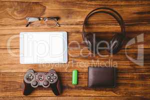 Tablet and glasses next to joystick music headphone and wallet