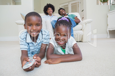 Happy siblings lying on the floor watching tv