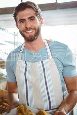 happy worker holding a basket of croissant