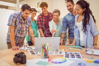 Happy creative business team using laptop in meeting