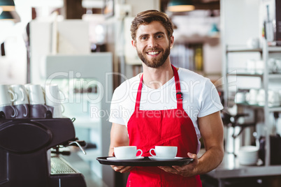 Handsome barista holding two cups of coffee