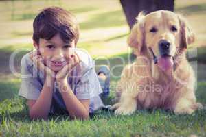Little boy looking at camera with his dog in the park