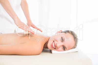 Beautiful blonde enjoying a bamboo roller massage smiling at ca