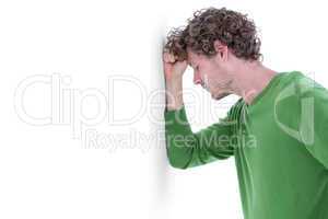 Sad casual man leaning against wall