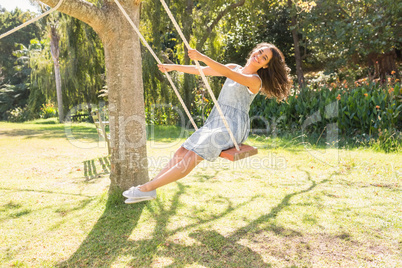 Pretty brunette swinging in park