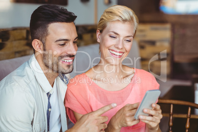 Cute couple sitting in cafe looking at smartphone