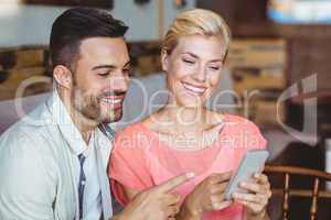 Cute couple sitting in cafe looking at smartphone