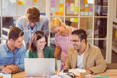 Happy creative business team using laptop in meeting