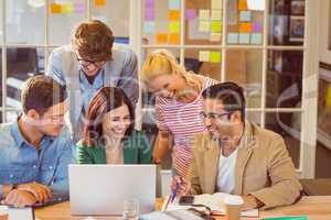 Happy creative business team using laptop in meeting