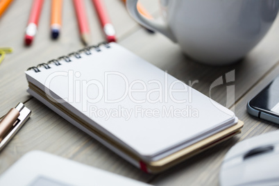 Notepad on the desk next to cup tablet and smartphone