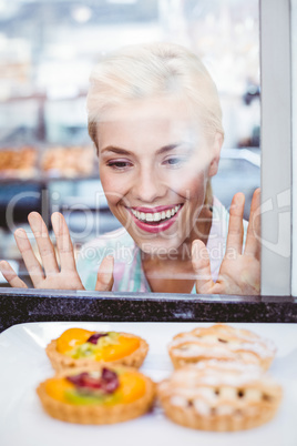 Puzzled pretty woman looking at a fruit pie through the glass