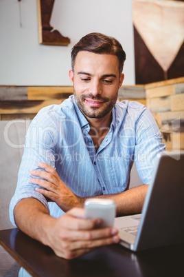 Smiling businessman sending a text message