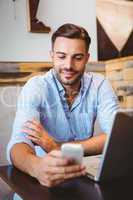 Smiling businessman sending a text message