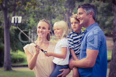 Happy family using a selfie stick in the park