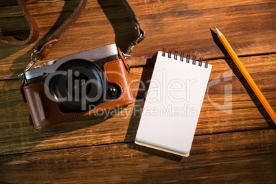 Camera next to the notepad and pen