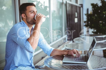 Young businessman drinking coffee beside a laptop